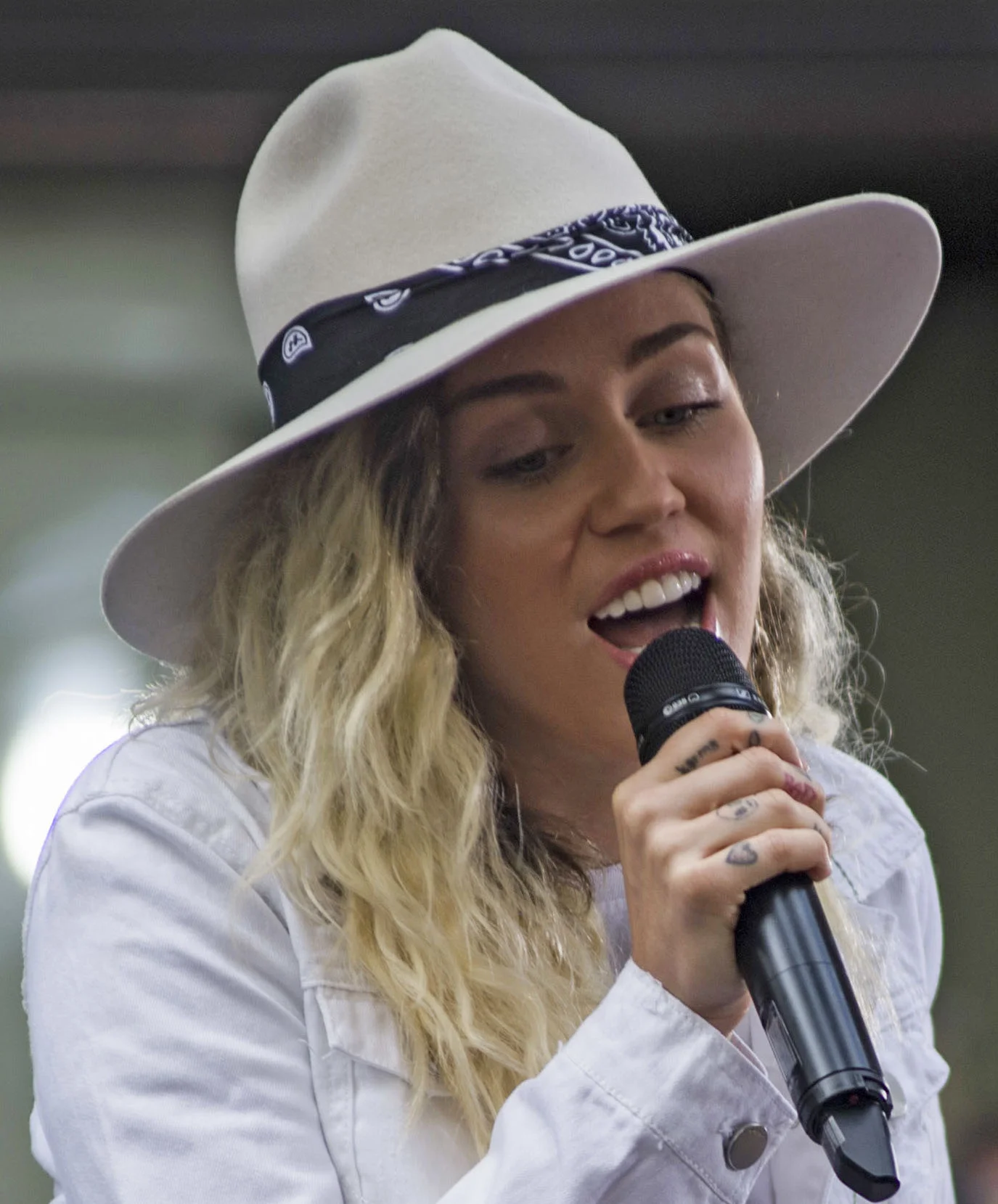 Miley Cyrus photographed singing at an outdoor television performance in 2017. Licensed image; it identifies the person only and is not evidence of any dental treatment.